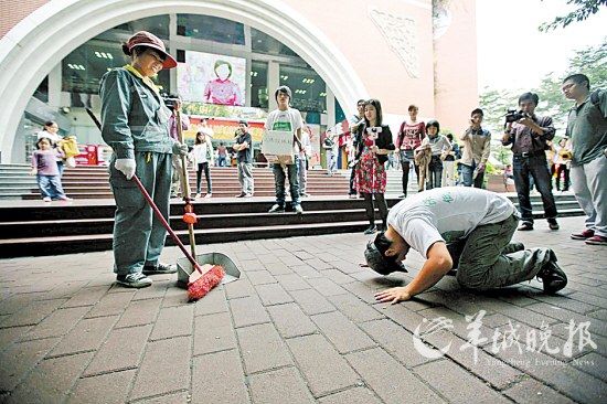 康毅跪在环卫工人面前，作出膜拜状