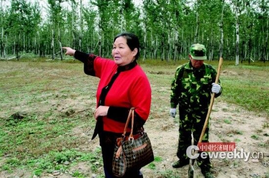 刘玉英，身后是她雇来看护林地的工人。《中国经济周刊》记者 肖翊 摄 