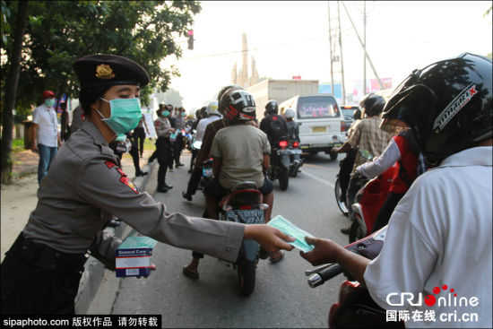 印尼森林火灾致空气污染女警街头发放免费口罩(组图)