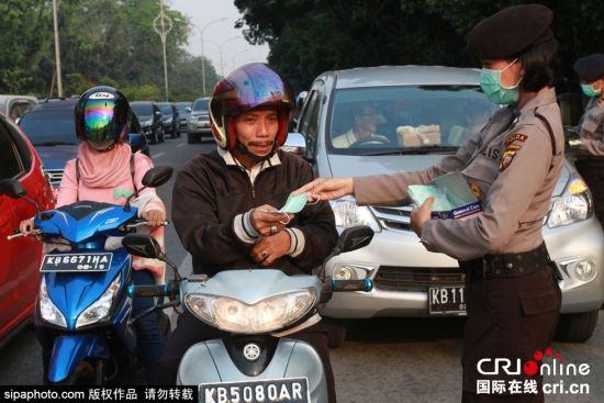 印尼森林火灾致空气污染女警街头发放免费口罩(组图)