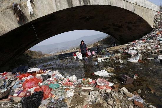 ▲2015年，大别山境内的一条河道的桥下布满各种生活垃圾。 图/视觉中国